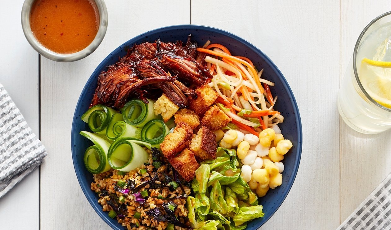 Bol de Porc effiloché BBQ avec Hominy, Salade de Kimchi à la Pêche Fumée et Croûtons de Pain de Maïs – - Recette