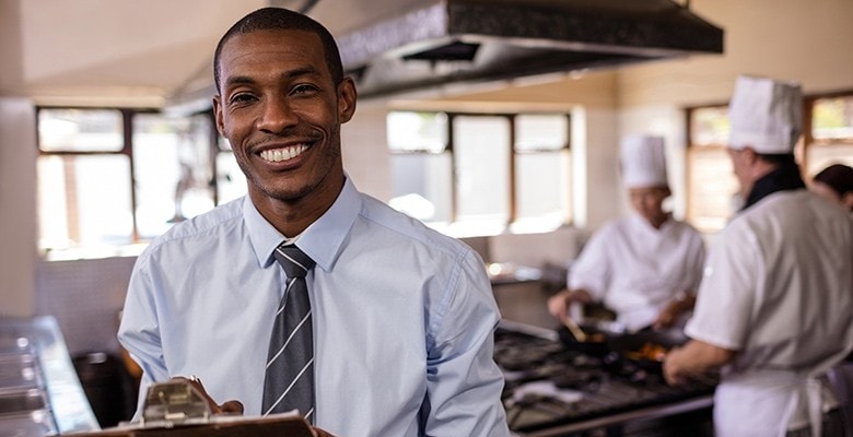 Restaurant manager with chefs cooking in the background