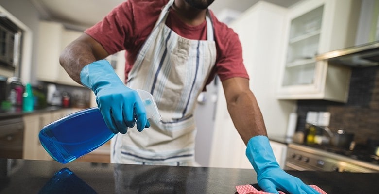 Chef cleaning kitchen counter tops with gloves