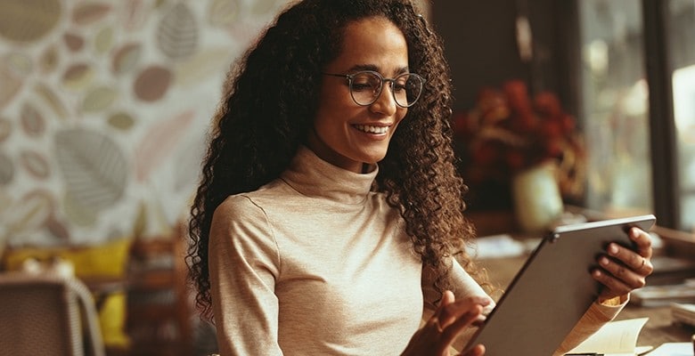 Woman smiling, using a tablet to manage her restaurant